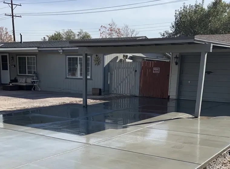 A house with a carport and a concrete driveway in front of it.