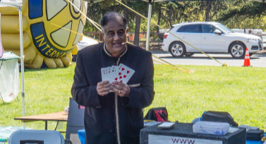 A man in a suit is holding a stuffed animal in front of a sign that says amazingvijay