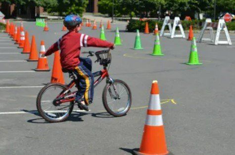 A young boy is riding a bike through traffic cones