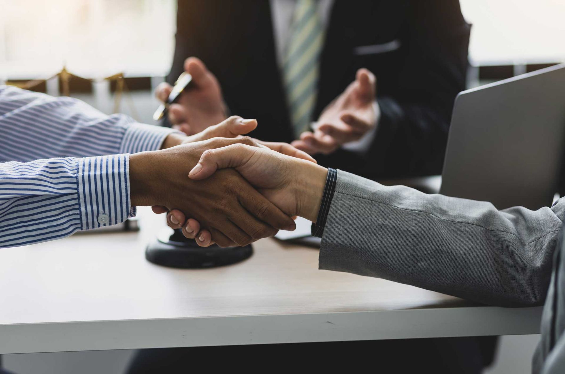 Two clients shaking hands across a conference table during a divorce mediation session Two clients shaking hands across a conference table during a divorce mediation session