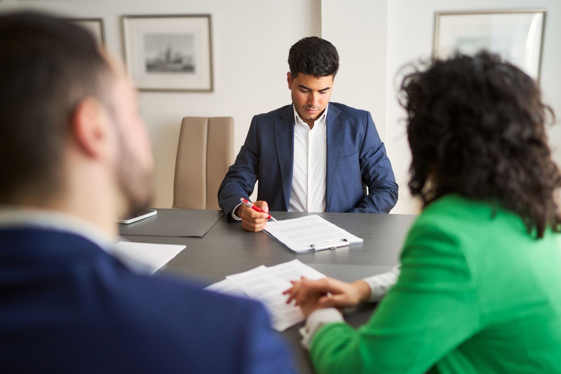 Three people are sitting at a table with papers in front of them.
