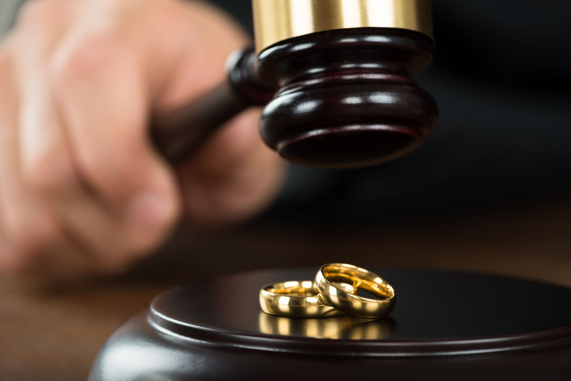 Judge's gavel near two gold wedding rings symbolizing divorce or legal separation.