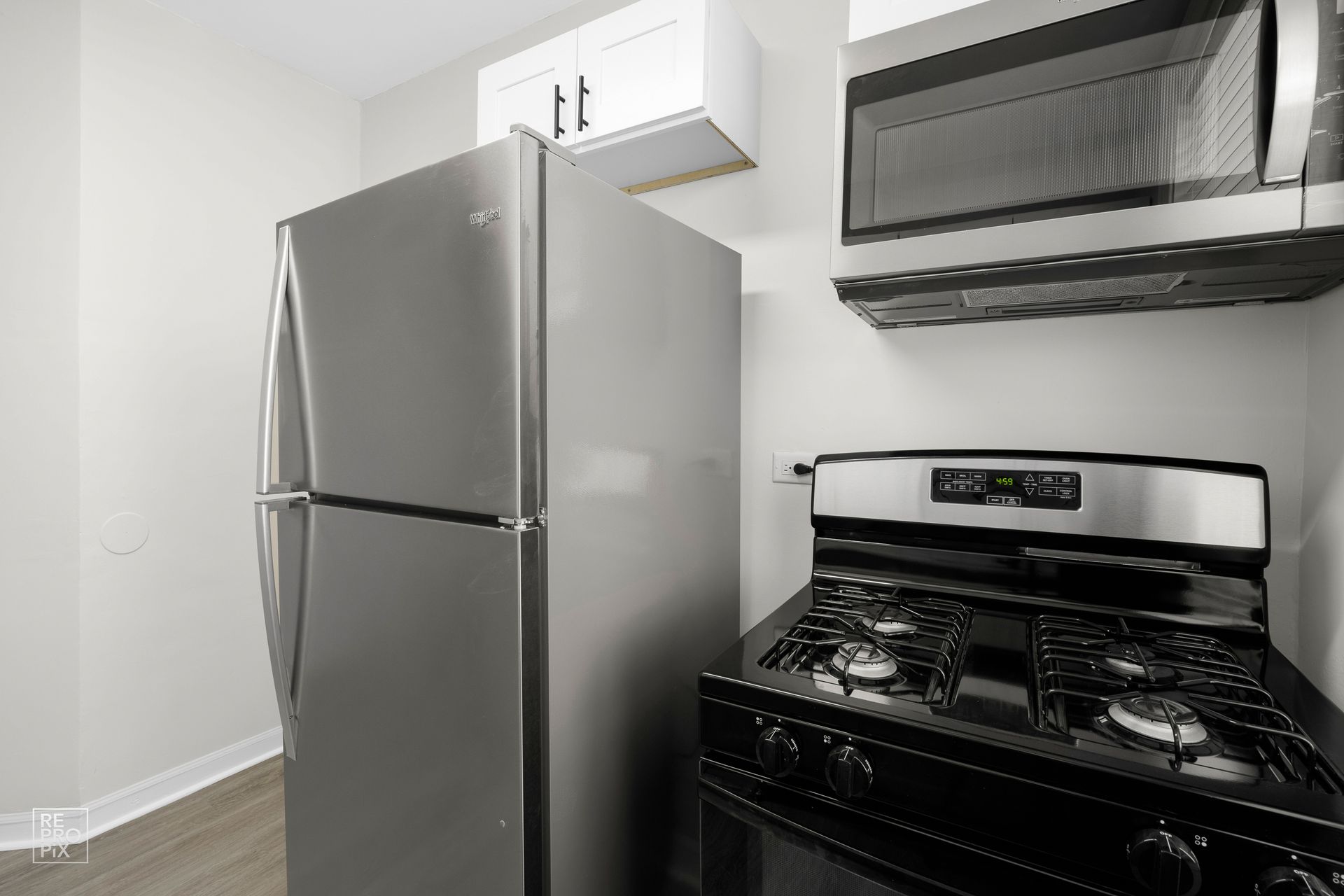 Stainless steel kitchen appliances: refrigerator, stove, and microwave. White cabinets above.