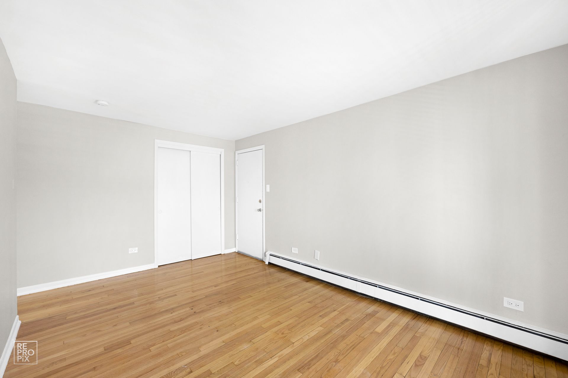 Empty room with wood floor, white walls, and closet.