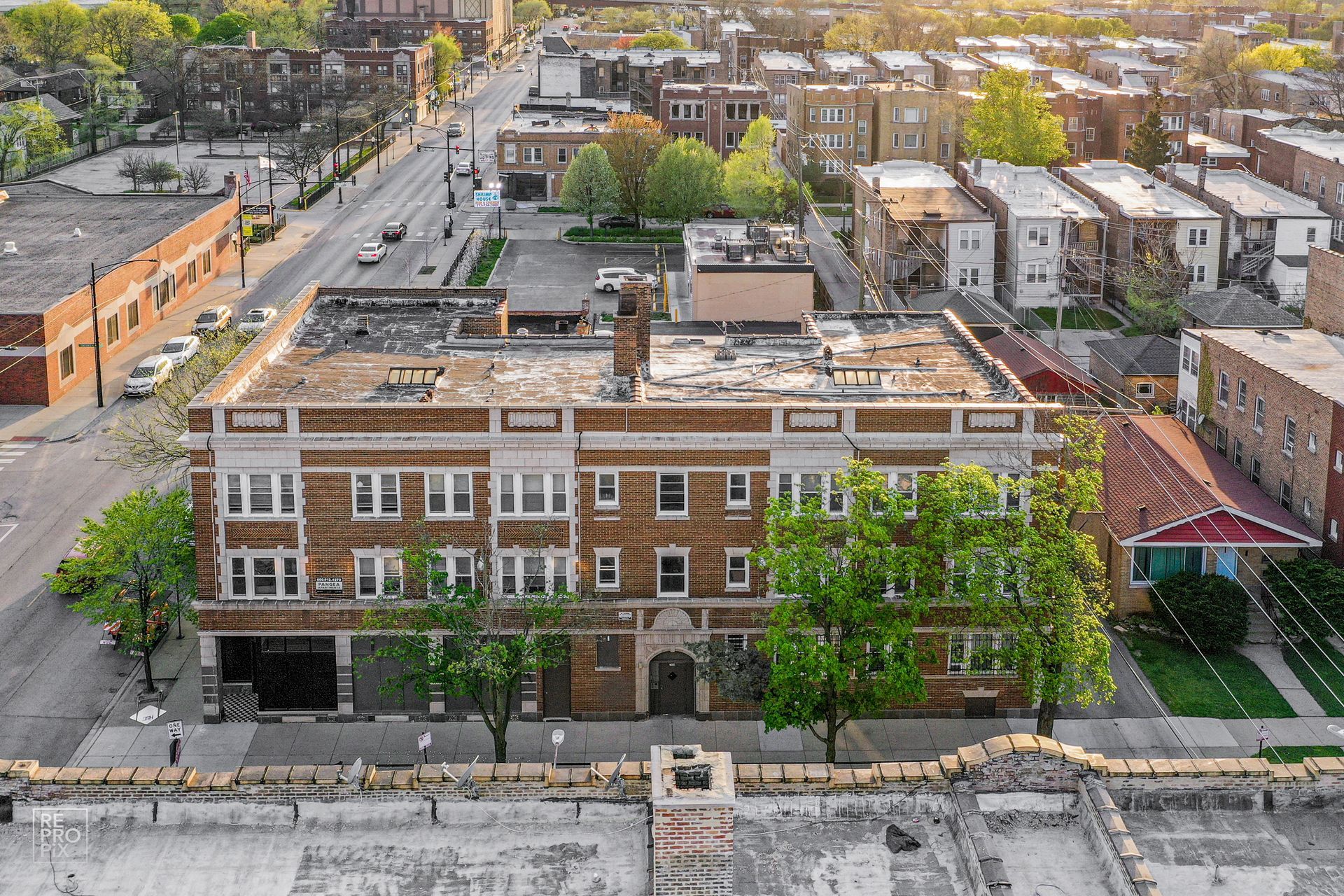 Aerial view of a three-story brick building with apartments, a street, and surrounding residential area.
