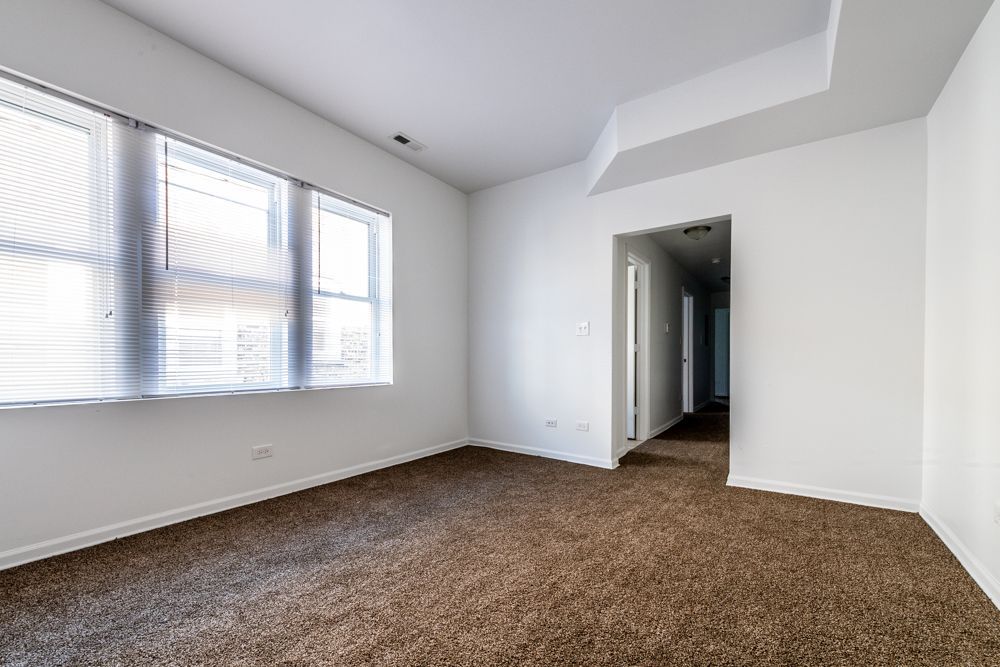 Empty room with brown carpet, white walls, and a window with blinds.