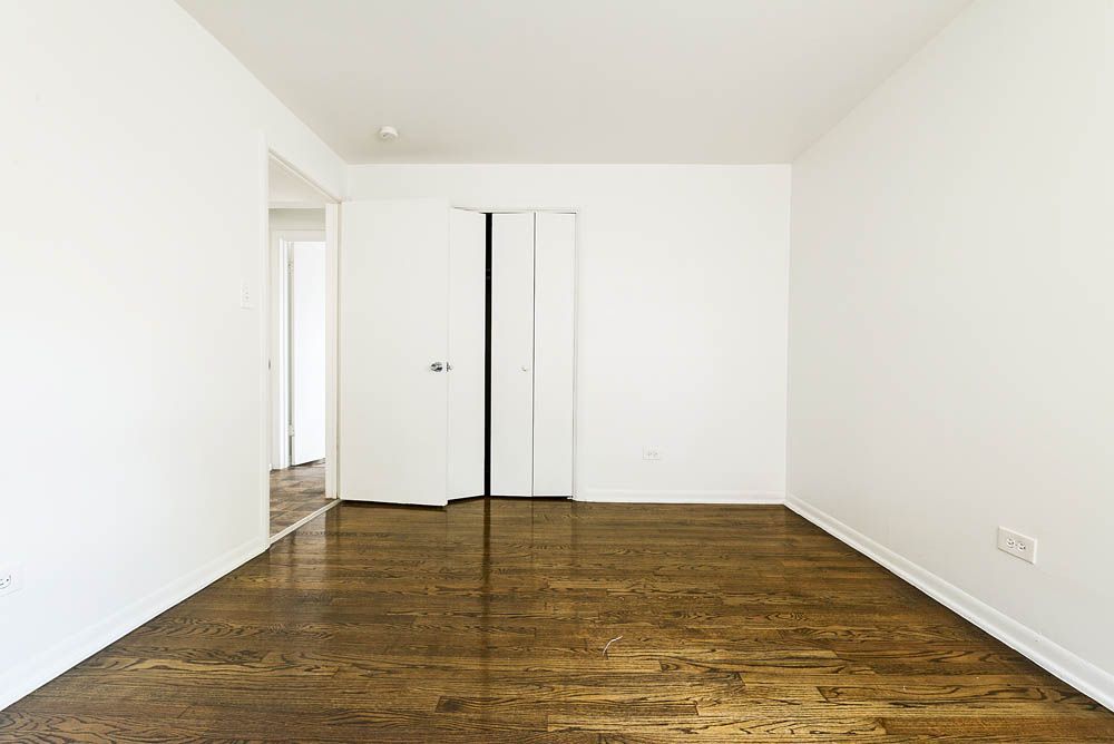 Empty room with hardwood floors, white walls, and a closet.