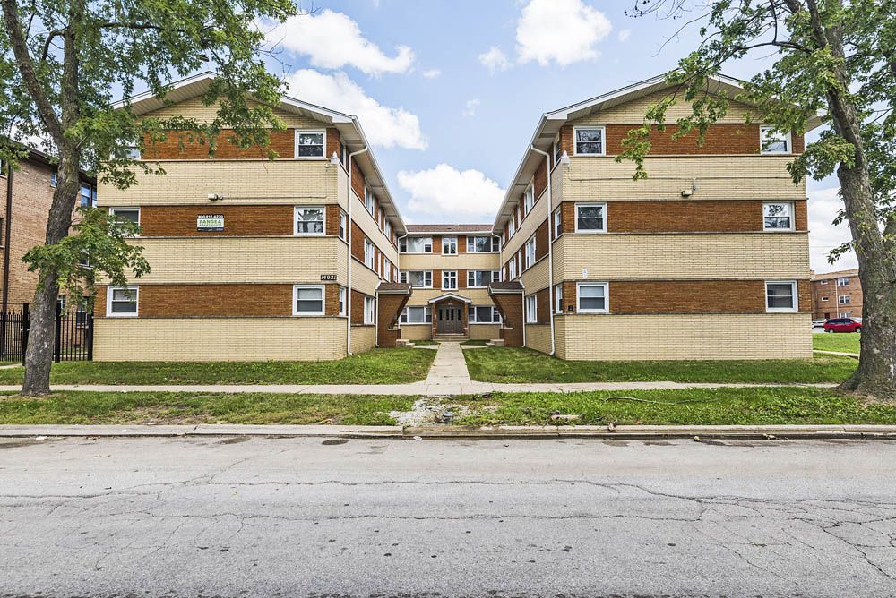Apartment building with brick and beige facade, three stories high, with a central walkway.