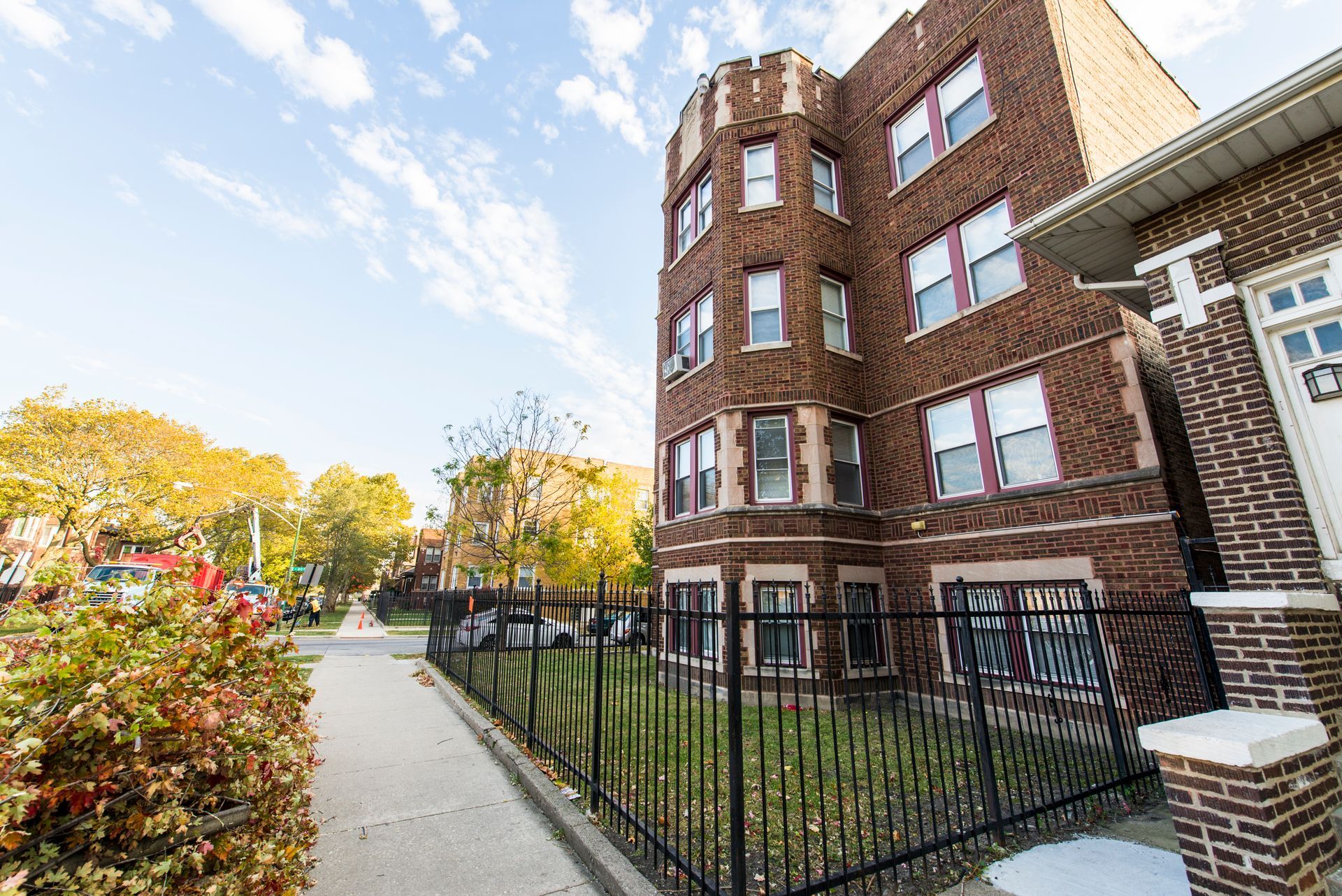 Brick apartment building with a wrought-iron fence on a sunny day.