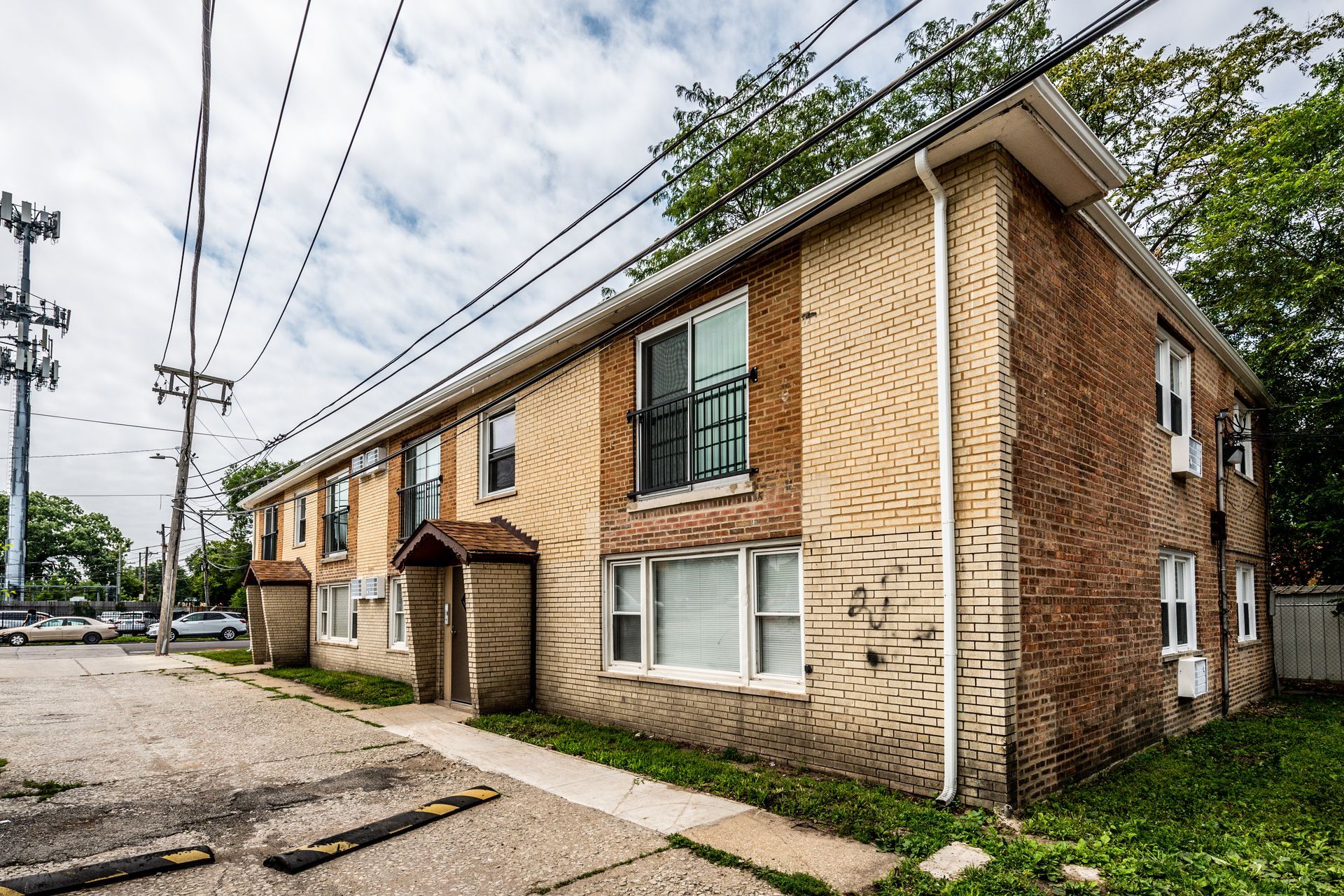 Two-story brick apartment building with drive in front and power lines overhead.