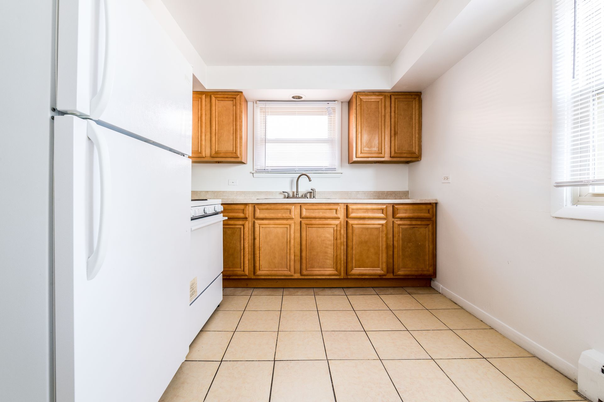 Kitchen with light brown cabinets, white appliances, and beige tile floor.