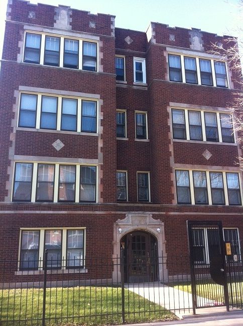 Brick apartment building with decorative stonework and wrought iron fence.