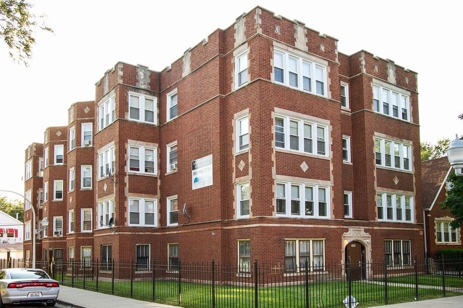 Red brick apartment building with white window trim, next to a street.