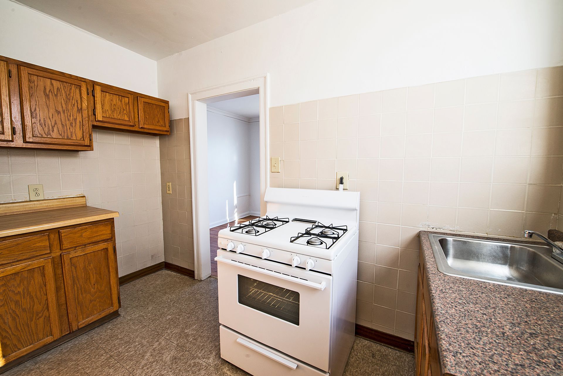Kitchen with brown cabinets, white stove, and a stainless steel sink.