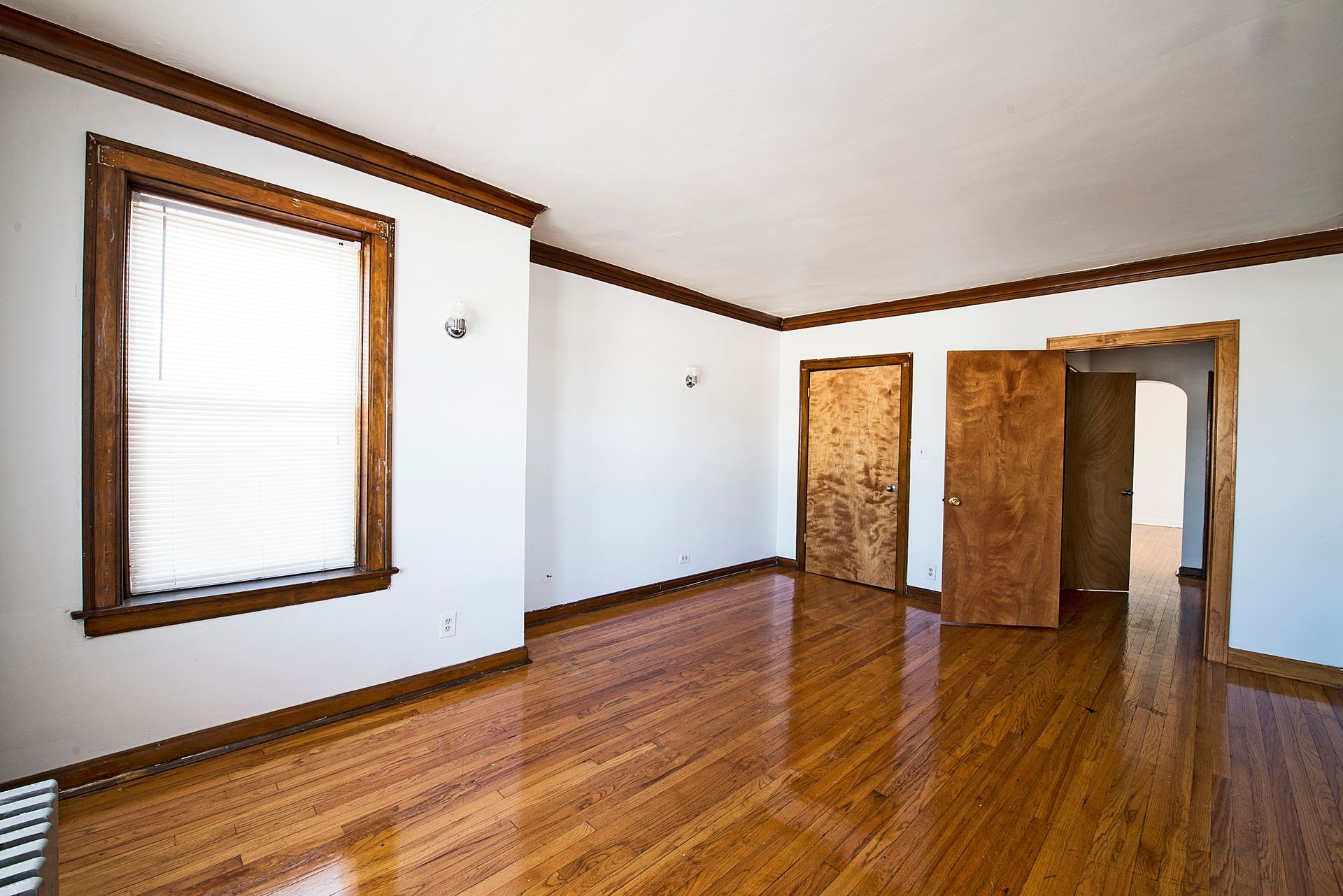 Empty room with wood floors, brown trim, and two doorways.