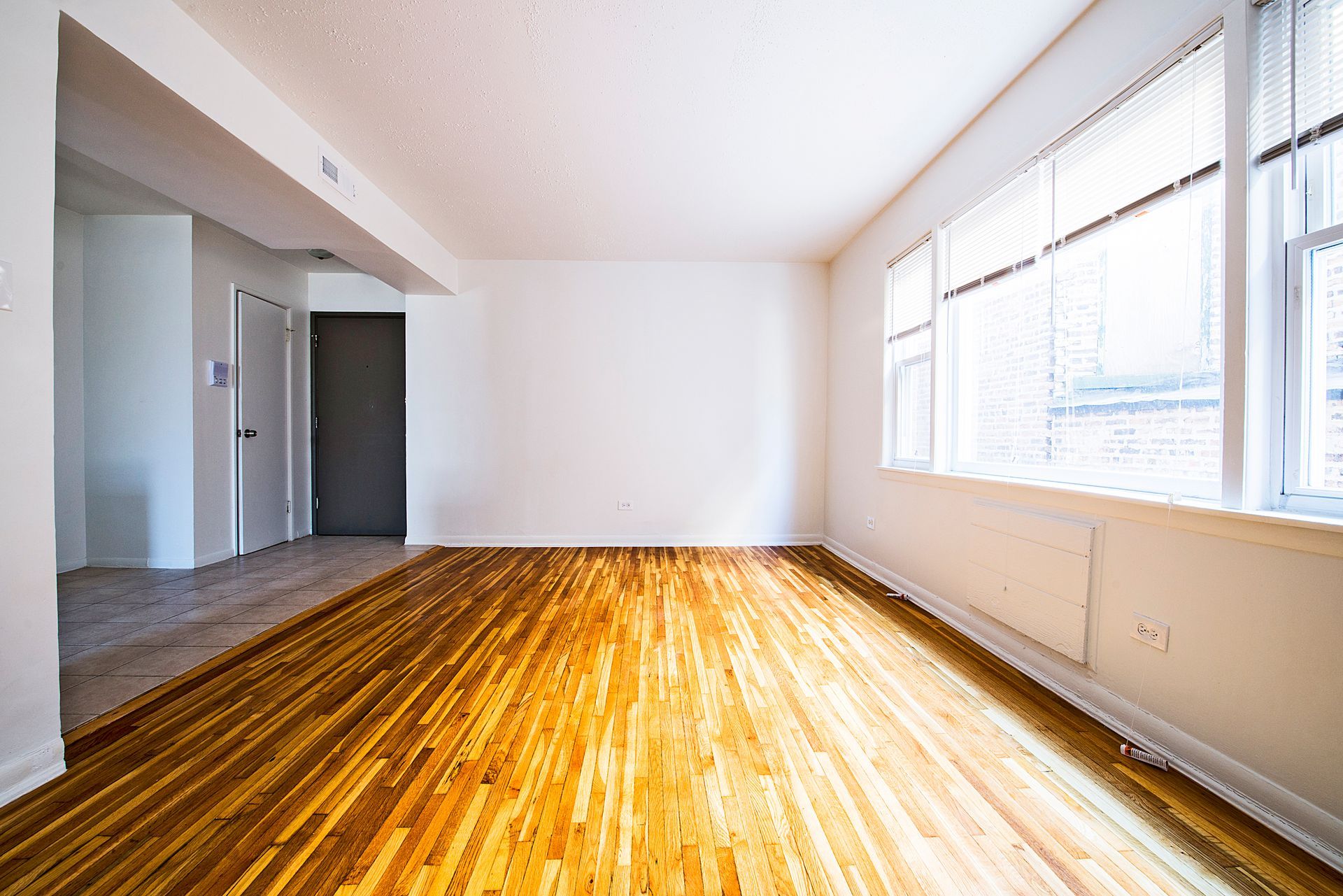 Empty room with wooden floor, white walls, and a window.