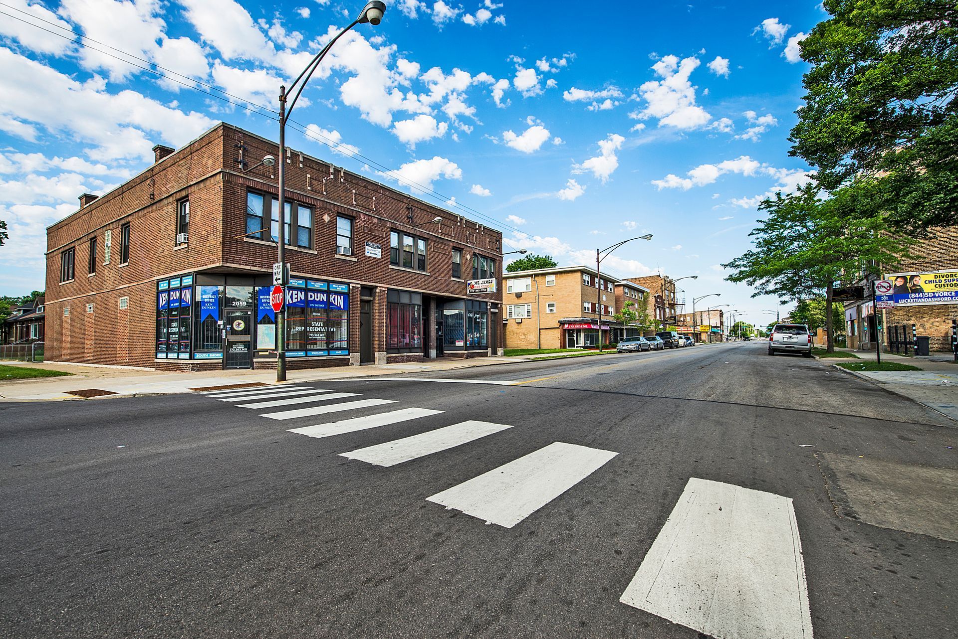 Street scene with brick buildings, crosswalk, blue sky.