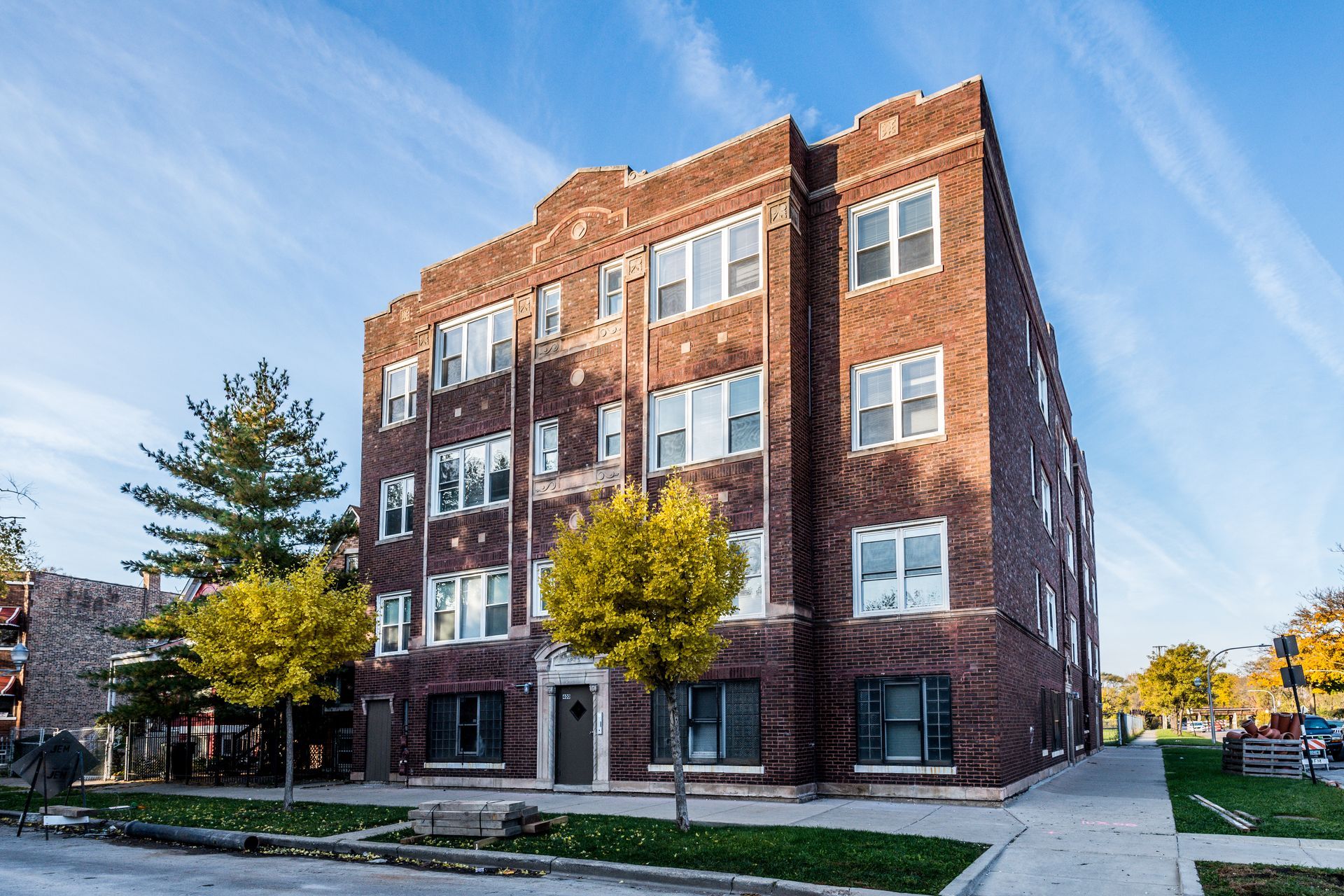 Red brick apartment building with white window frames and a blue sky.