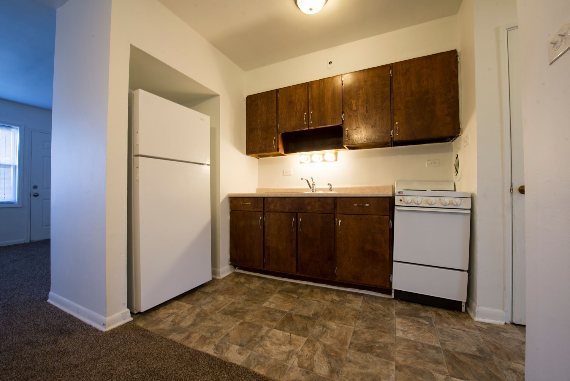 Small kitchen with a white refrigerator, brown cabinets, and a white stove.