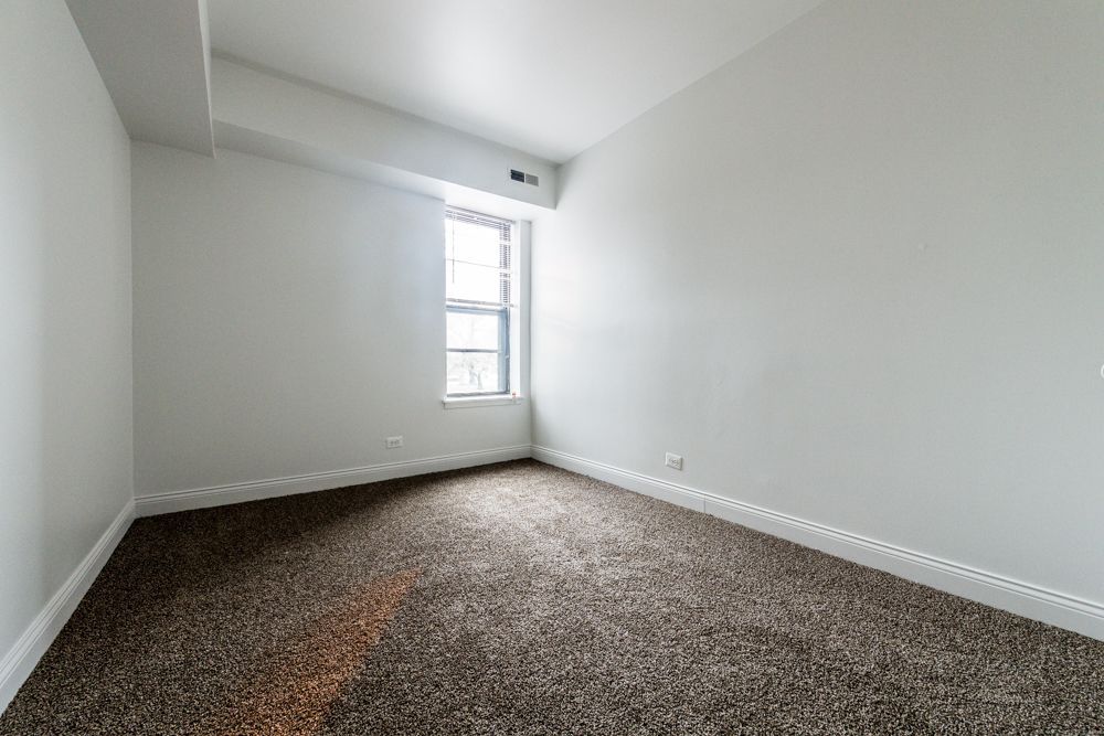 Empty room with brown carpet, white walls, and a window.