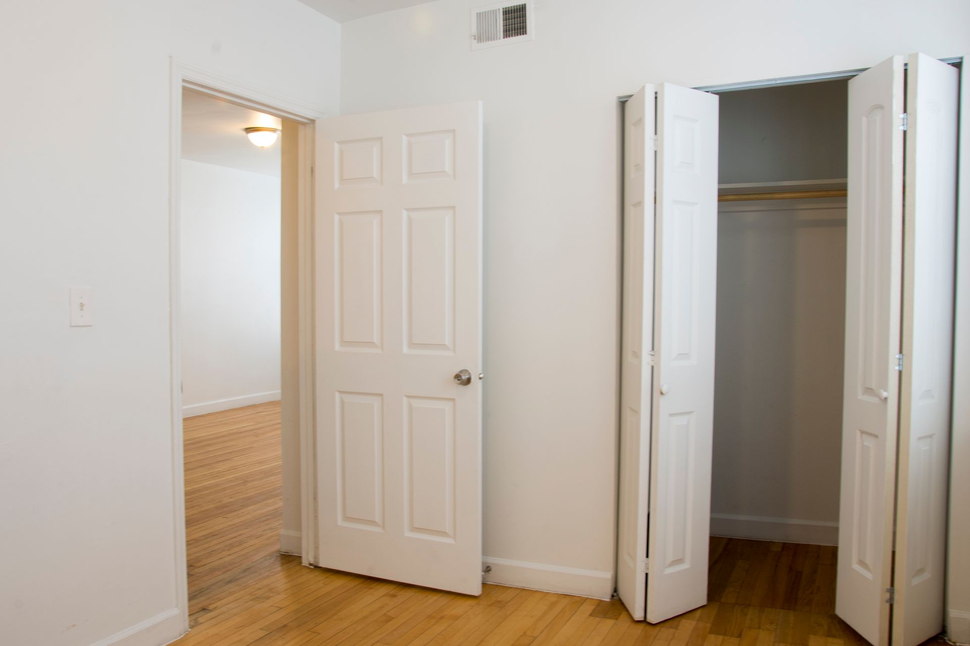 Empty bedroom interior with open doors and closet.