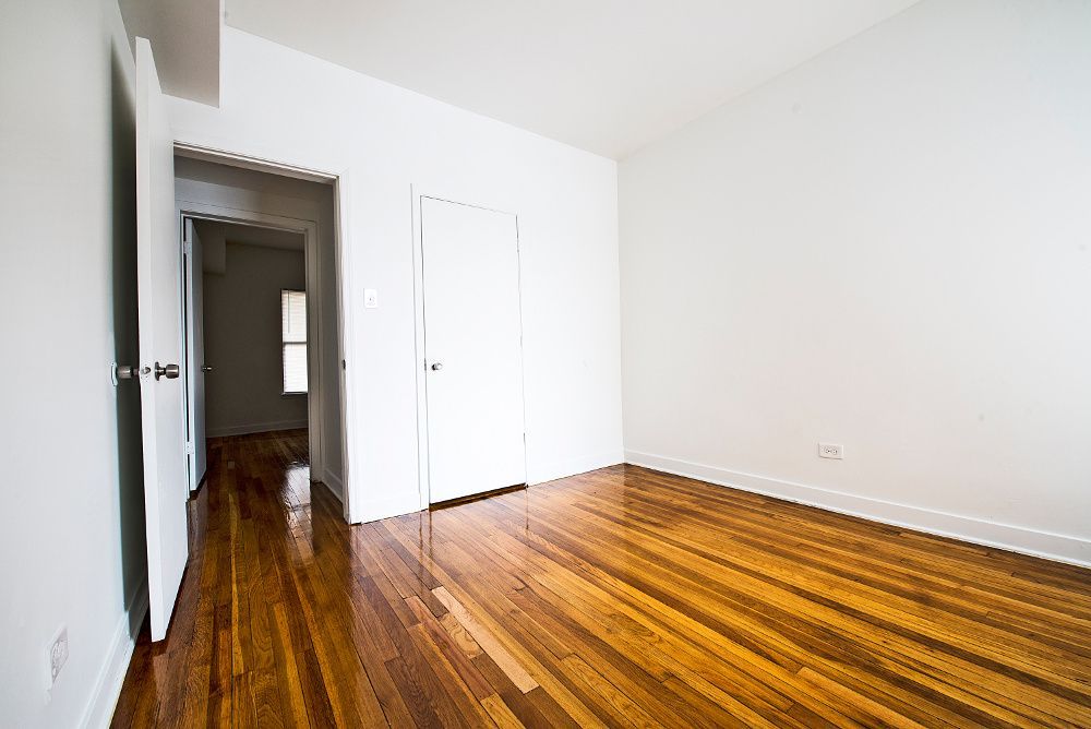 Empty room with wood flooring, white walls, and two closed doors.