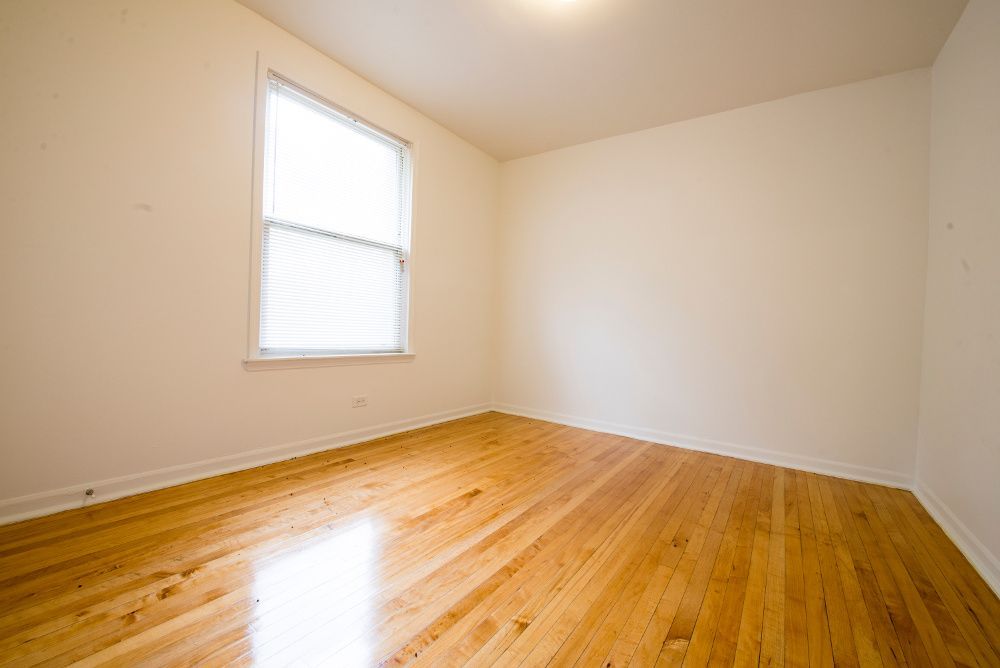 Empty room with hardwood floors, a window, and white walls.