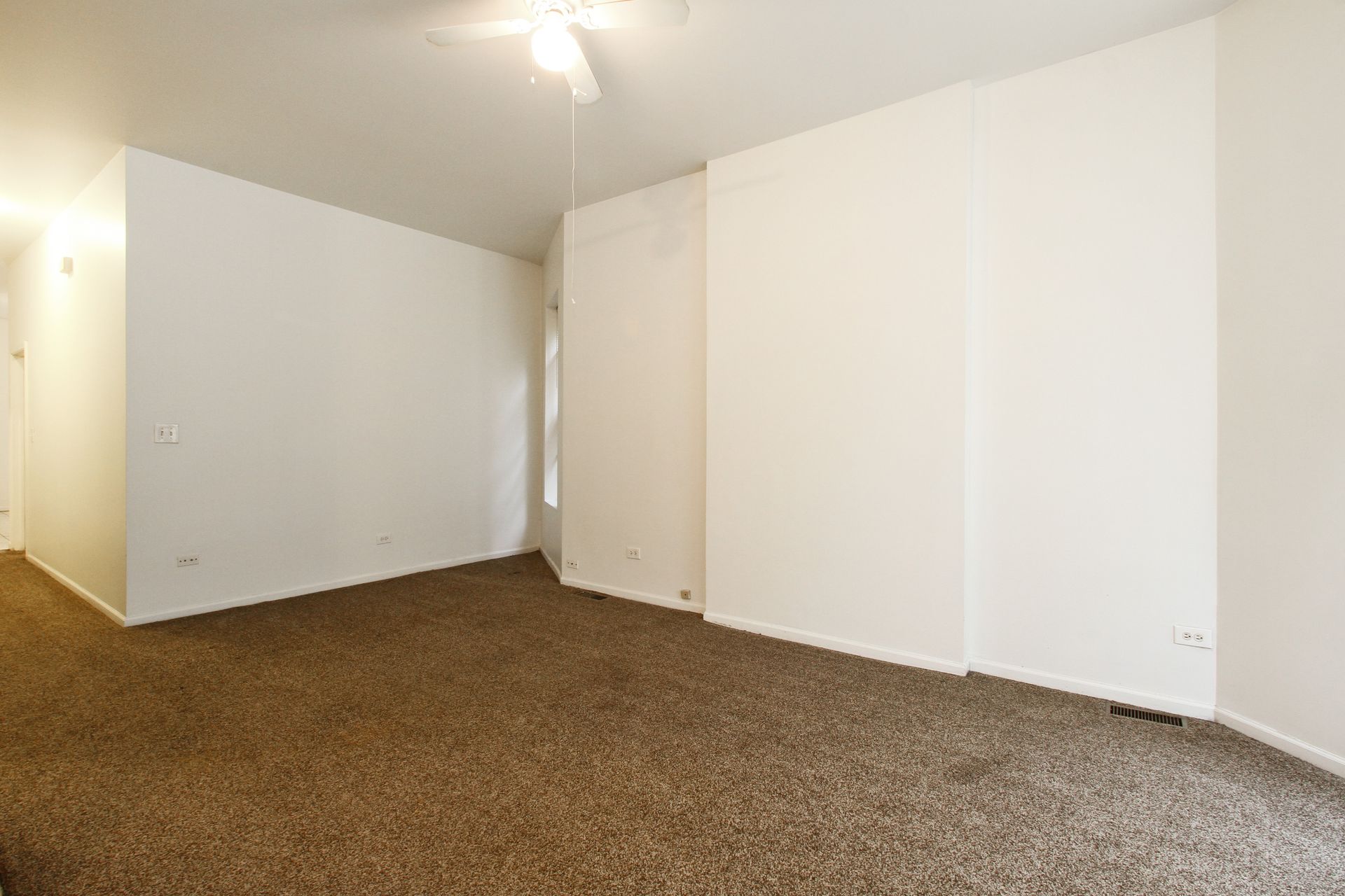 Empty room with beige carpet, white walls, and a ceiling fan.