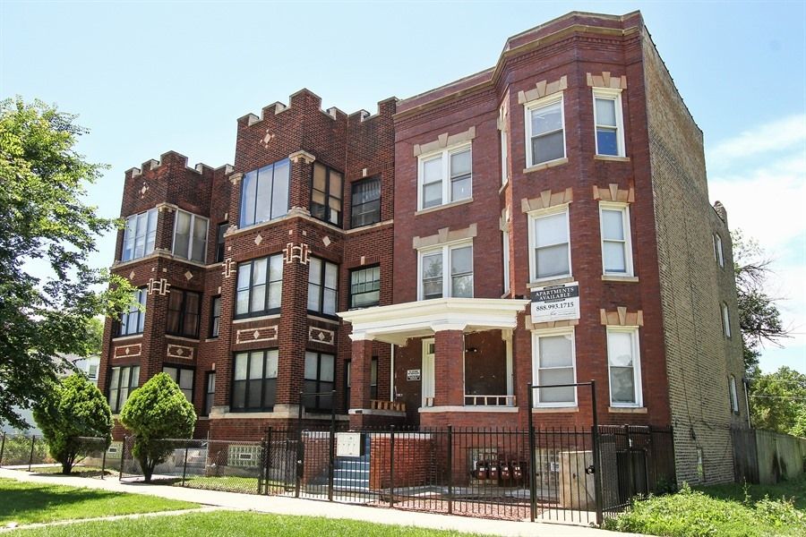 Red brick apartment building with bay windows and a wrought iron fence.