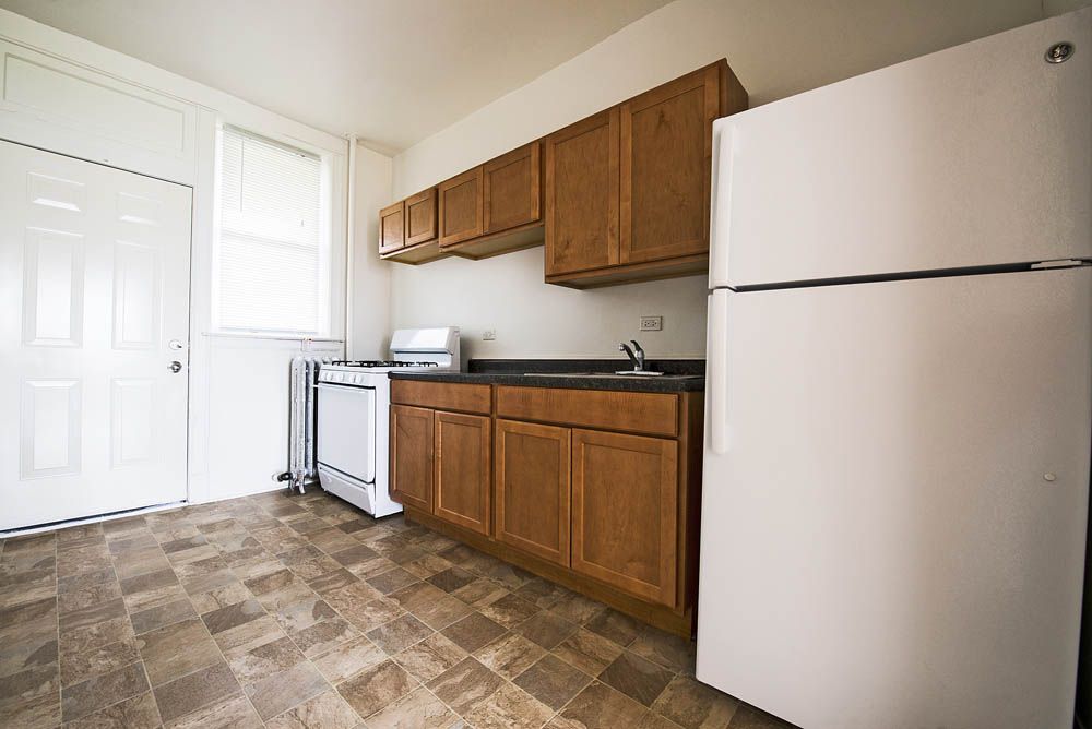 Kitchen with brown cabinets, white appliances, and a patterned floor.