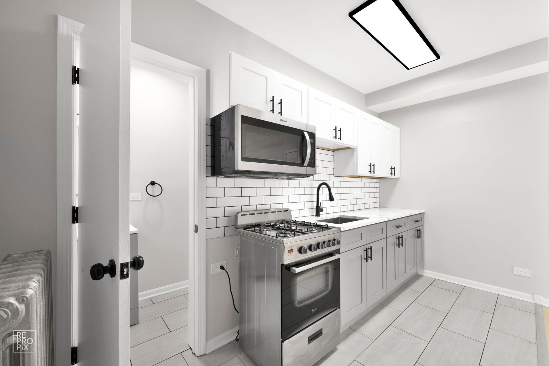 Small kitchen with stainless steel appliances, white cabinets, and subway tile backsplash.