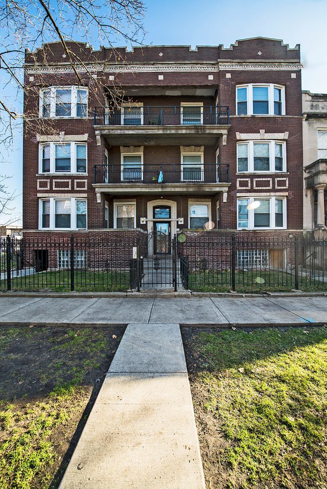 Brick apartment building with black fence and walkway.