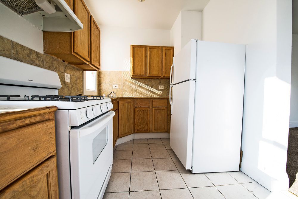 Kitchen with white appliances, wooden cabinets, and tile floor.