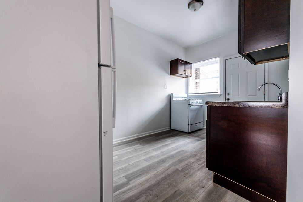 Kitchen with dark cabinets, white appliances, and gray flooring.