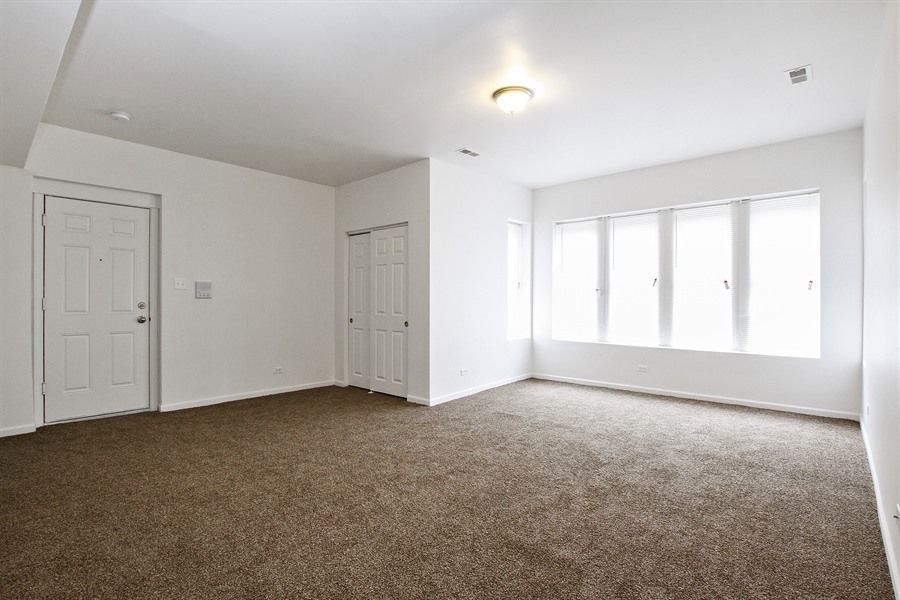 Empty room with brown carpet, white walls, and a window.
