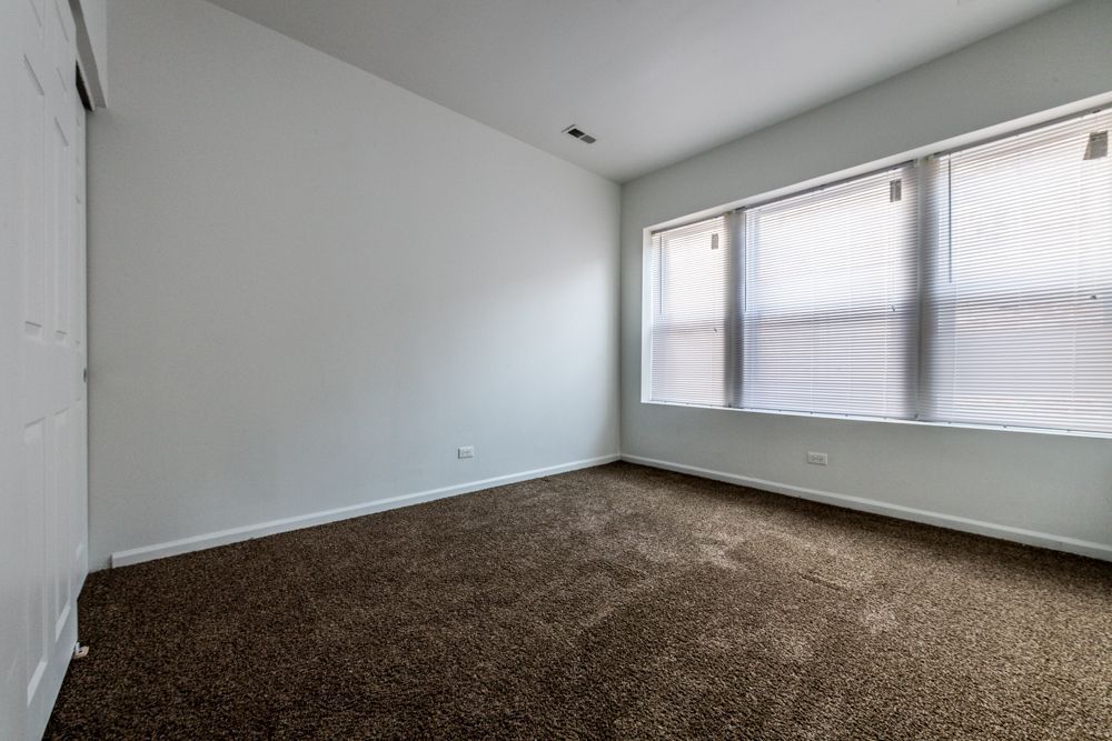 Empty room with brown carpet, white walls, and a window with blinds.