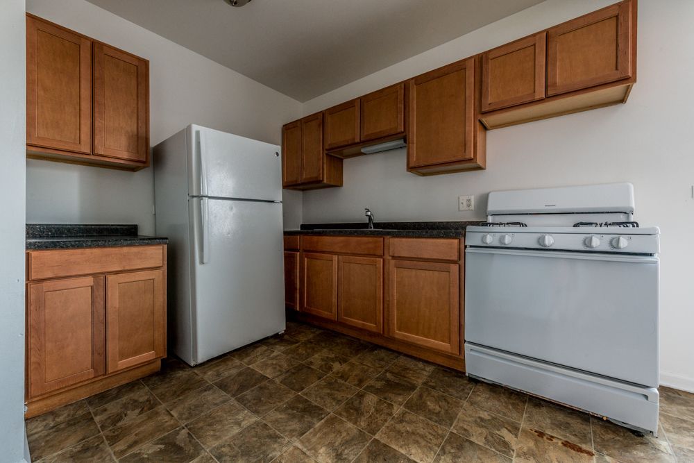 Kitchen with white appliances, brown cabinets, and a linoleum floor.