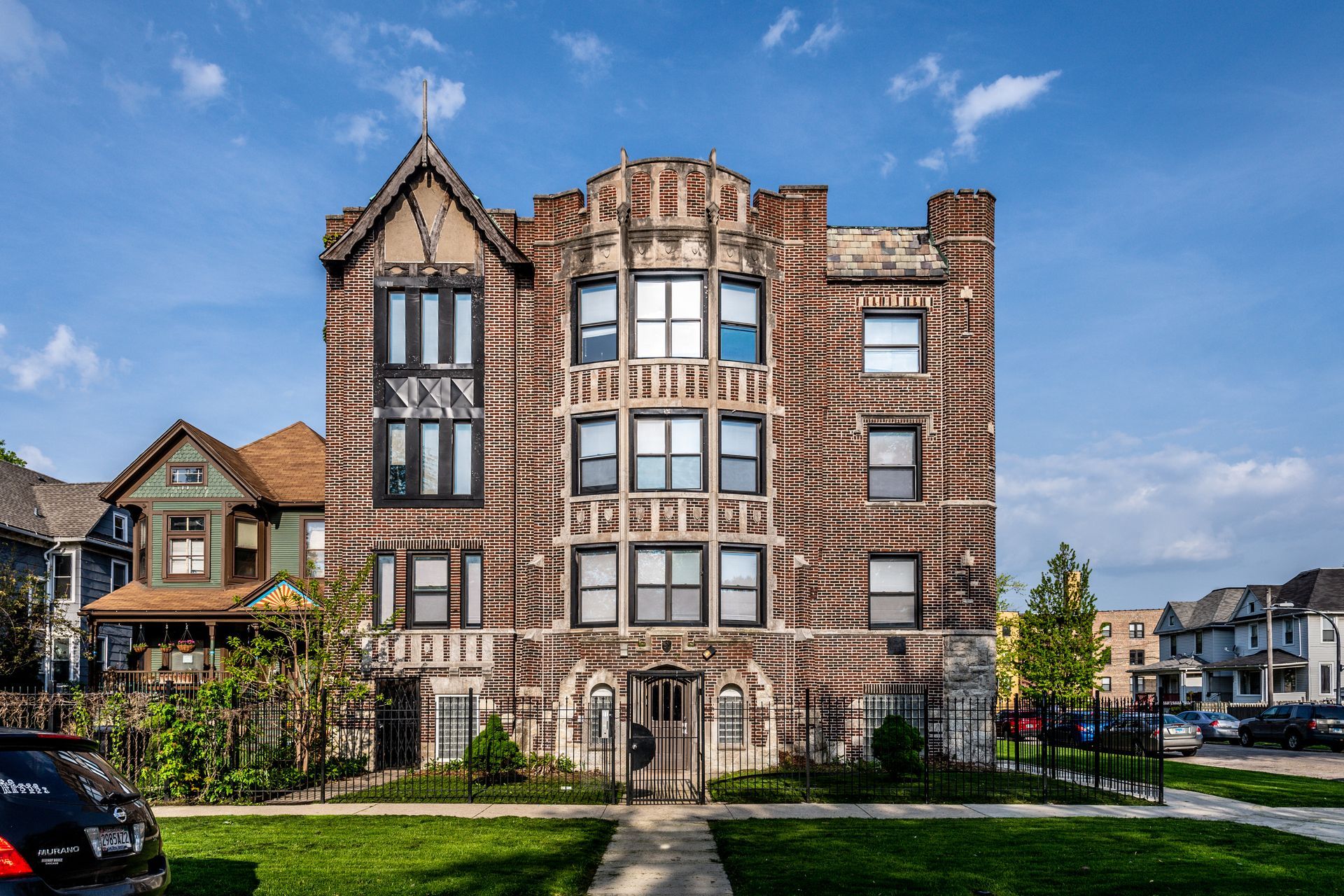 Four-story brick apartment building with brown and white striped facade and ornate details on a sunny day.
