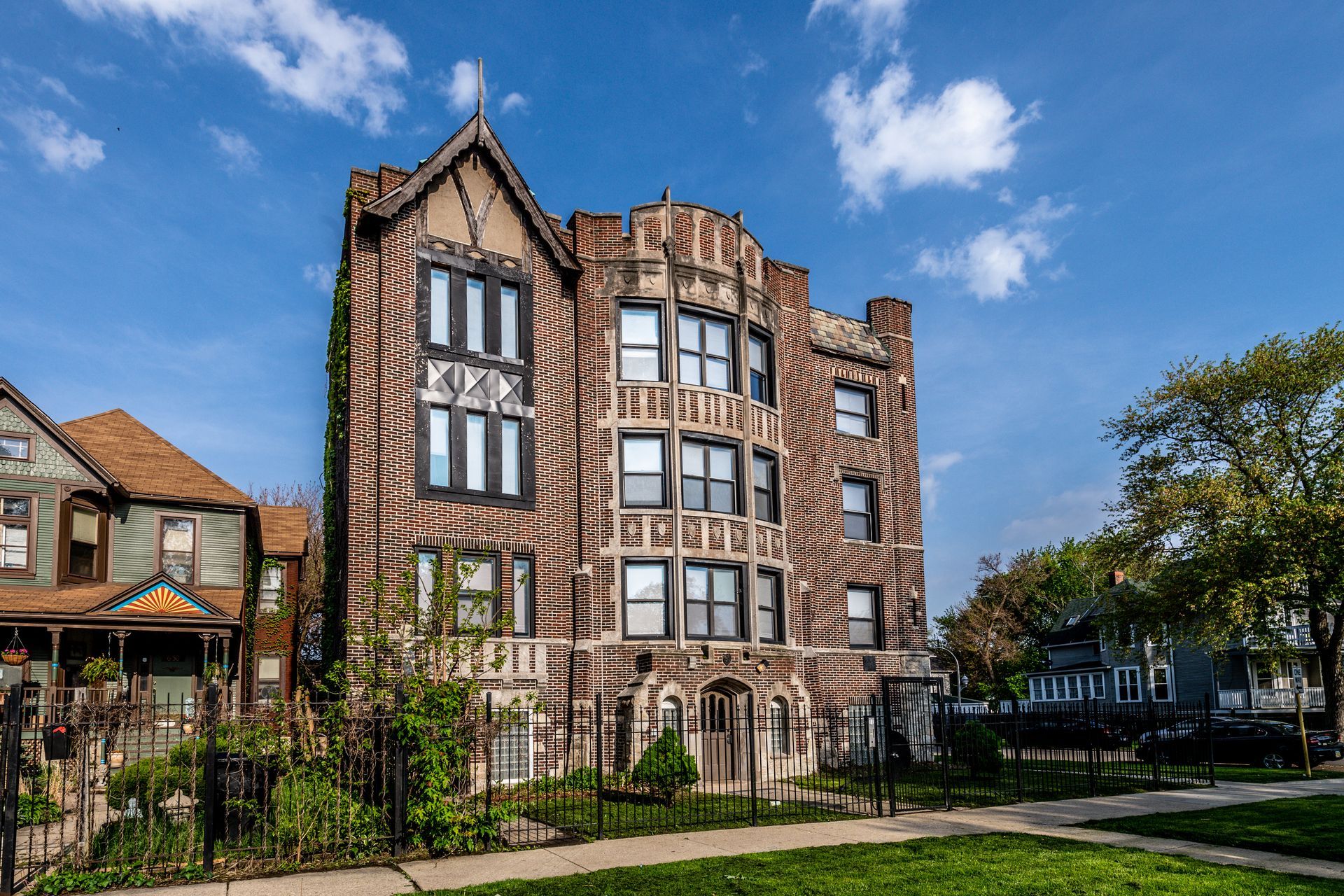 Multi-story brick building with Tudor-style details, dark window frames, and arched entryway.