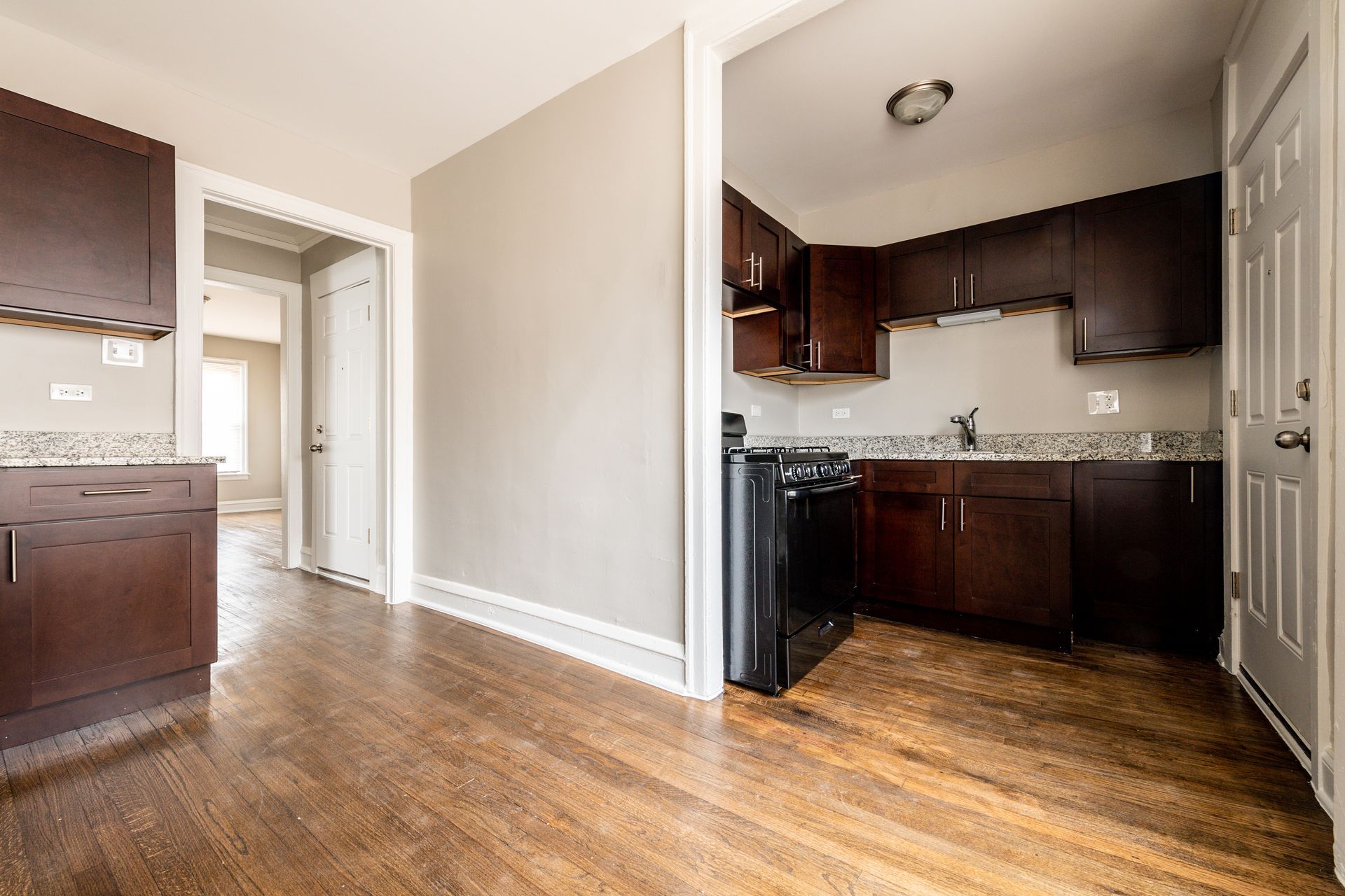 Kitchen with dark wood cabinets, wooden floor, and a black stove.
