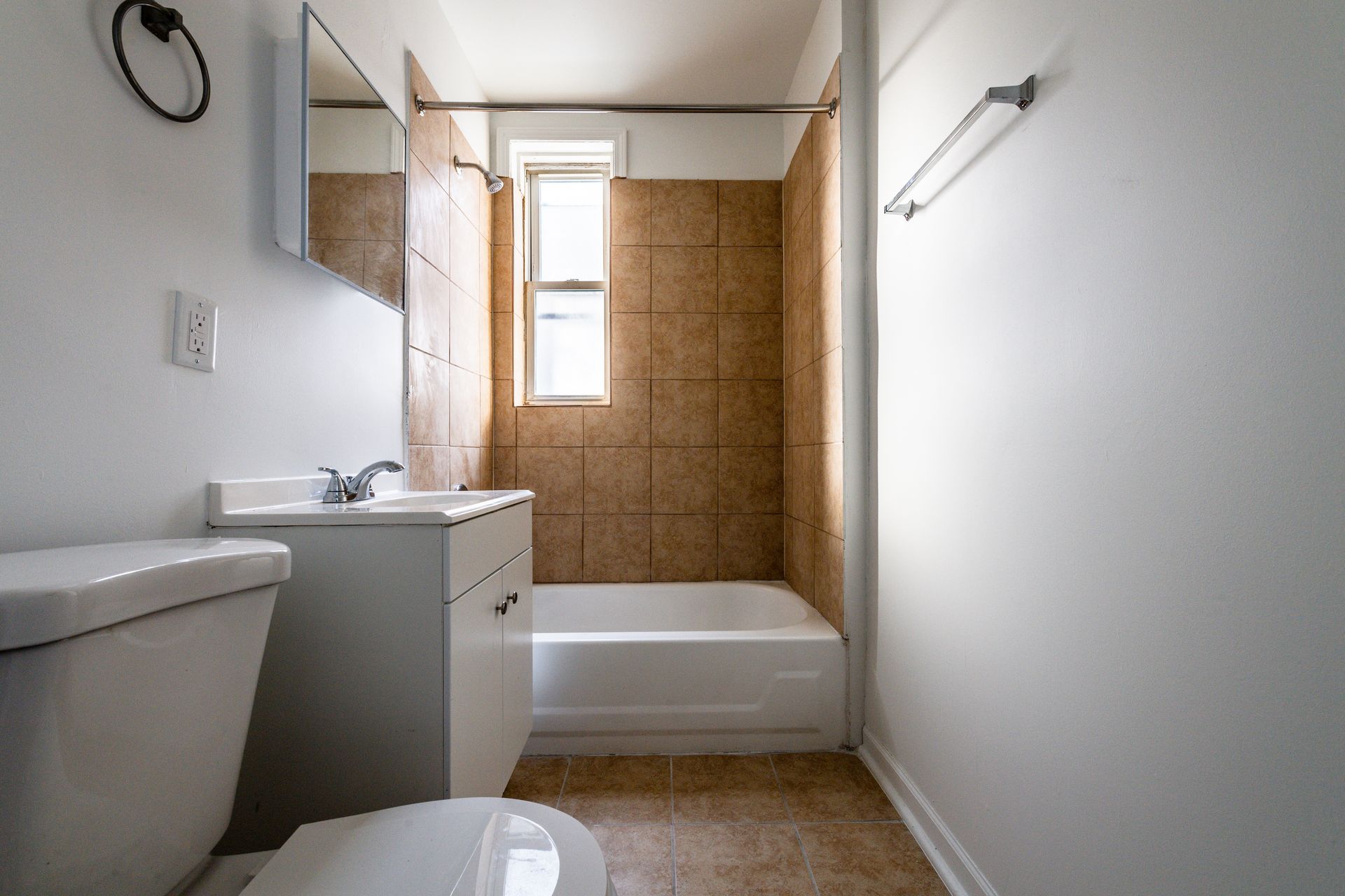 Bathroom with white walls, toilet, vanity, and beige tiled shower/tub.