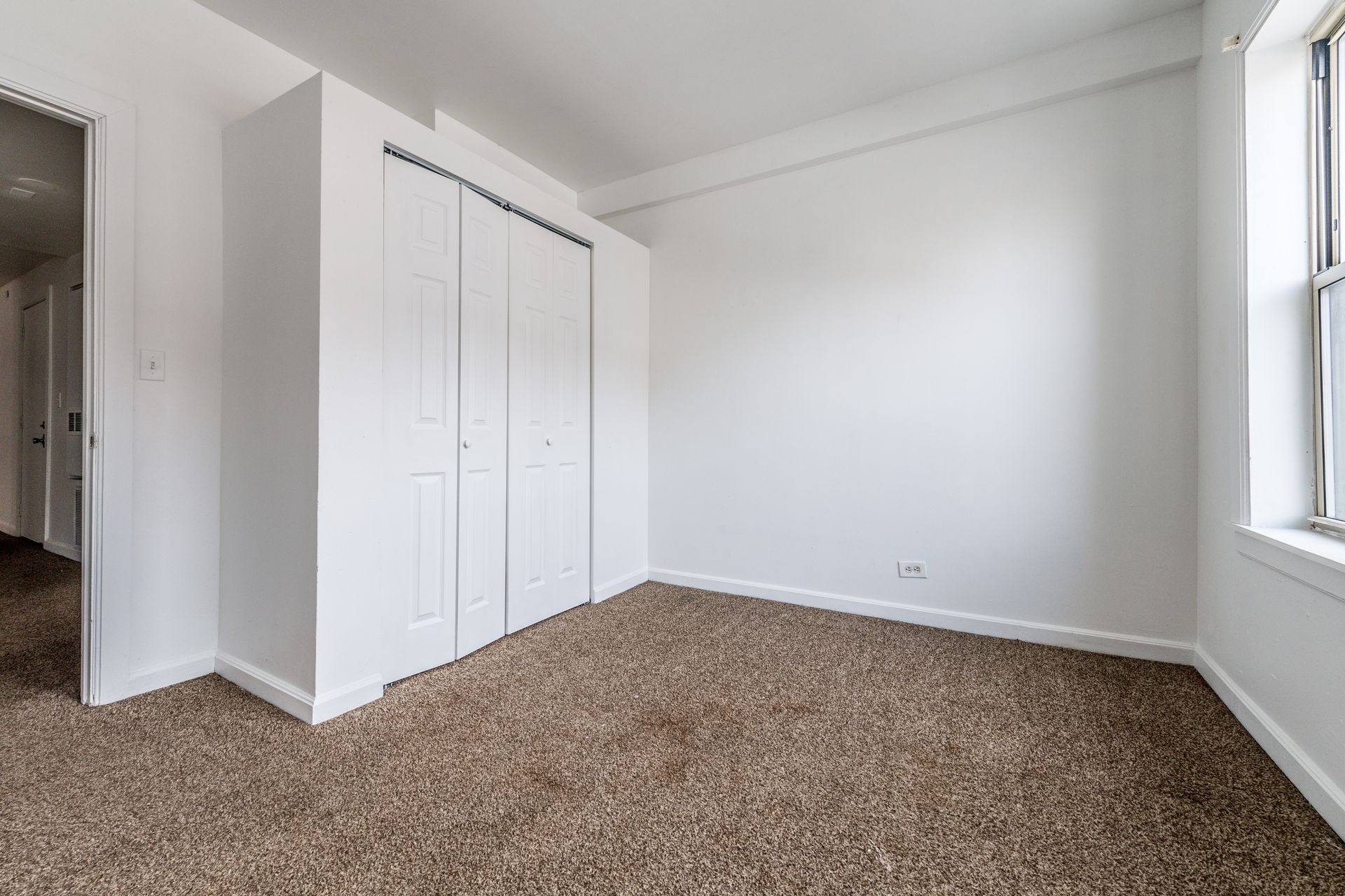 Empty room with white walls, carpet, and a closet.