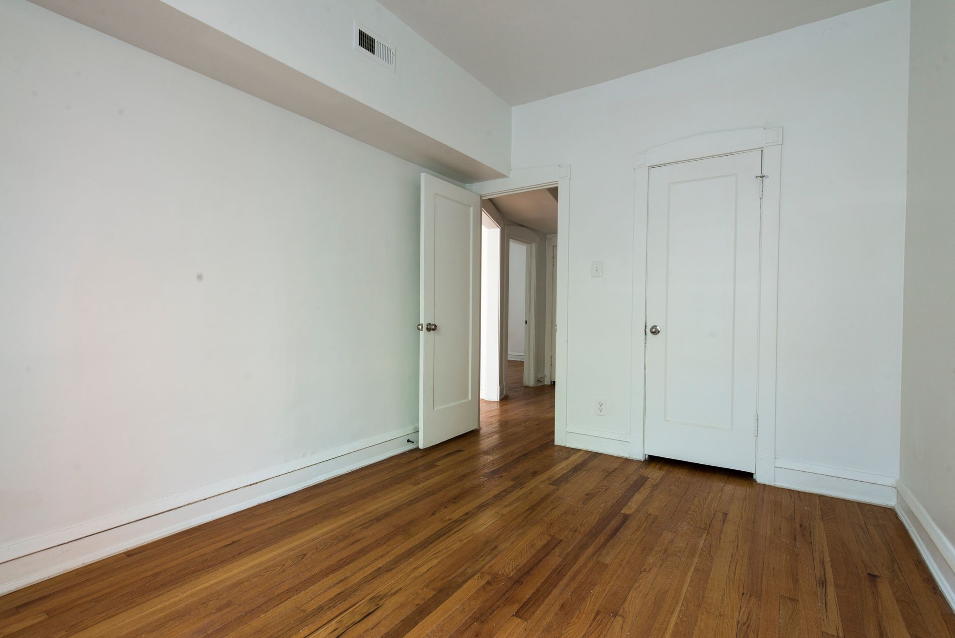 Empty room with wood floor, white walls and doors.