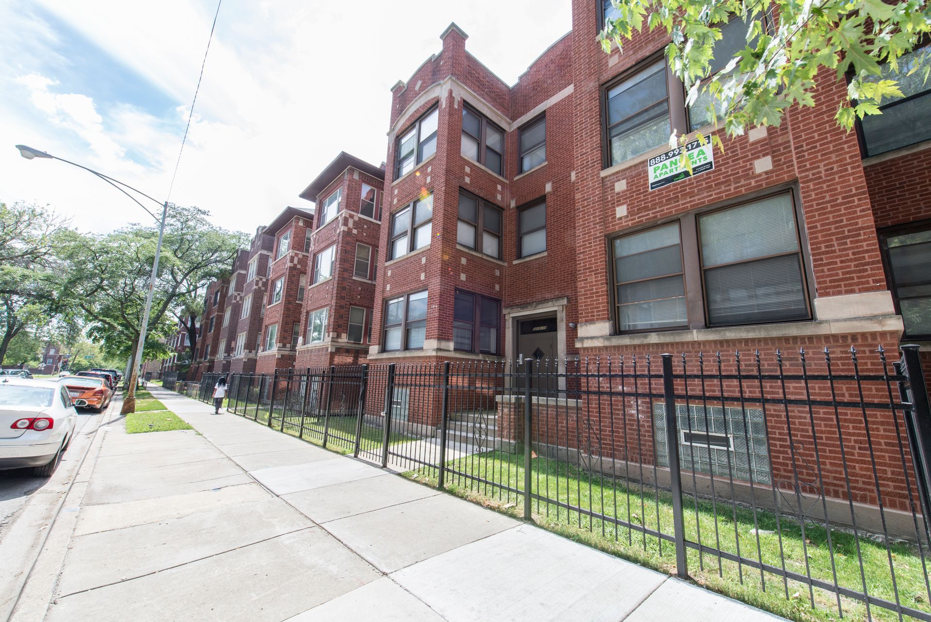 Brick apartment building with black fence along the sidewalk.