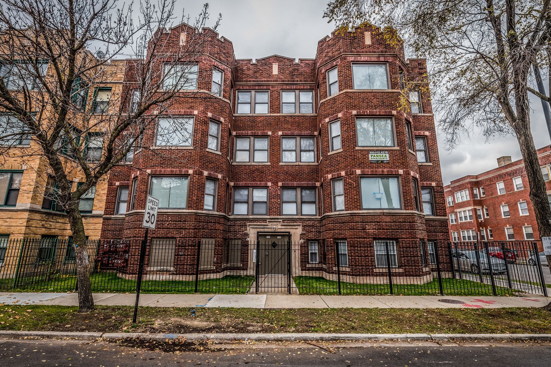 Brick apartment building with decorative details; gray sky.