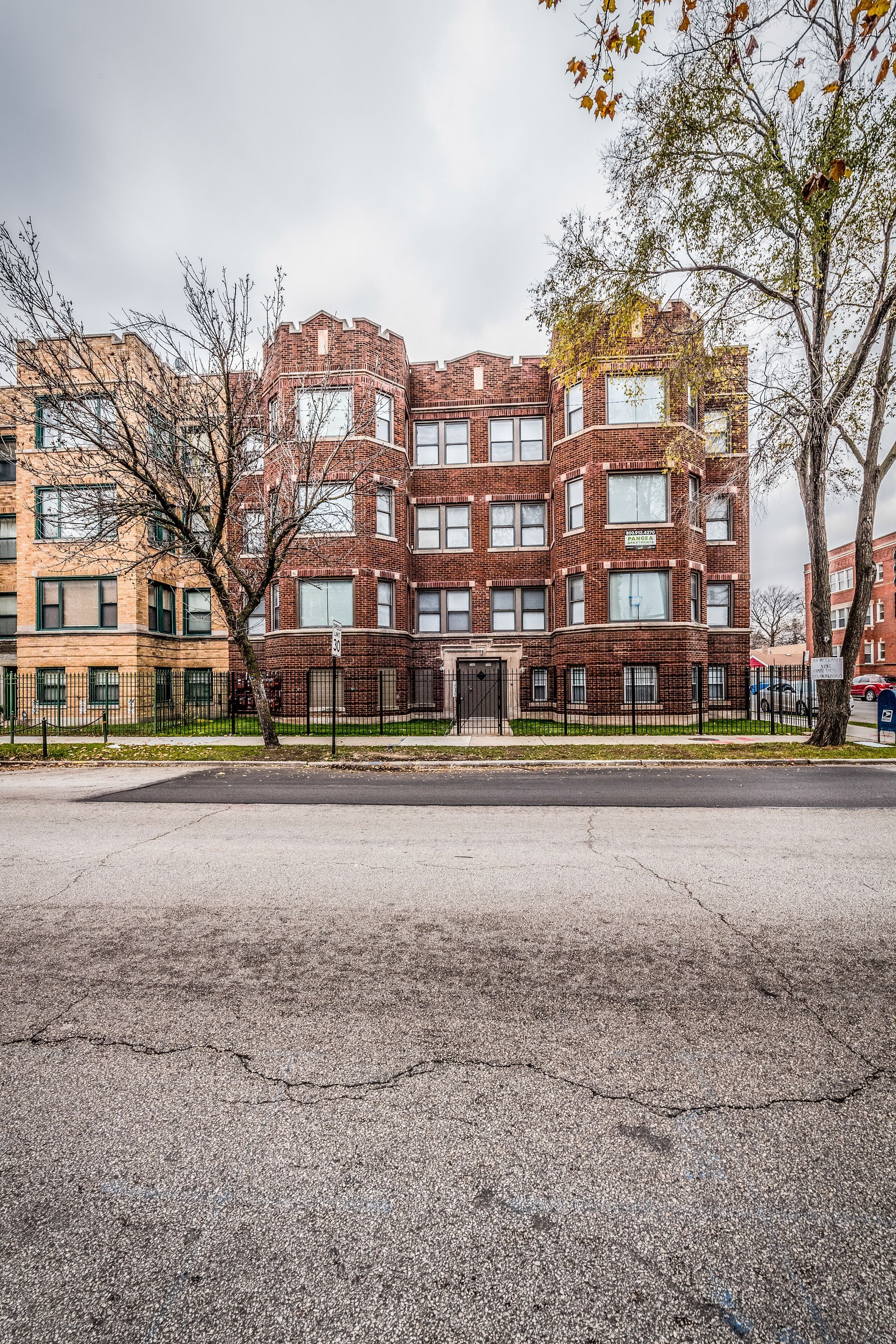 Brick apartment building on a street, overcast sky.