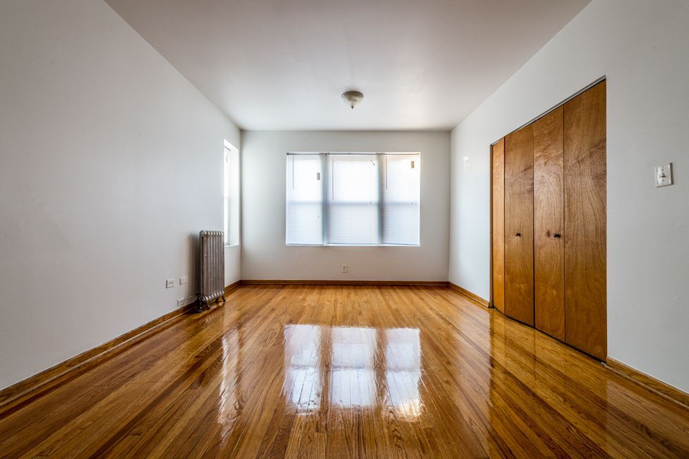 Empty room with hardwood floors, white walls, and a wooden closet.