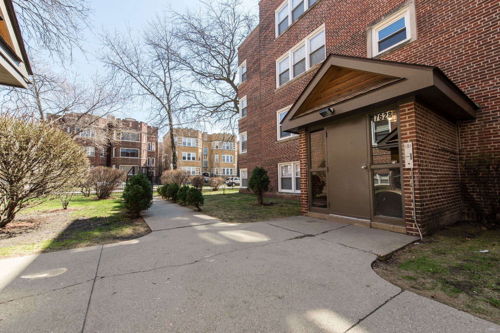 Brick apartment building entrance with covered doorway and walkway.