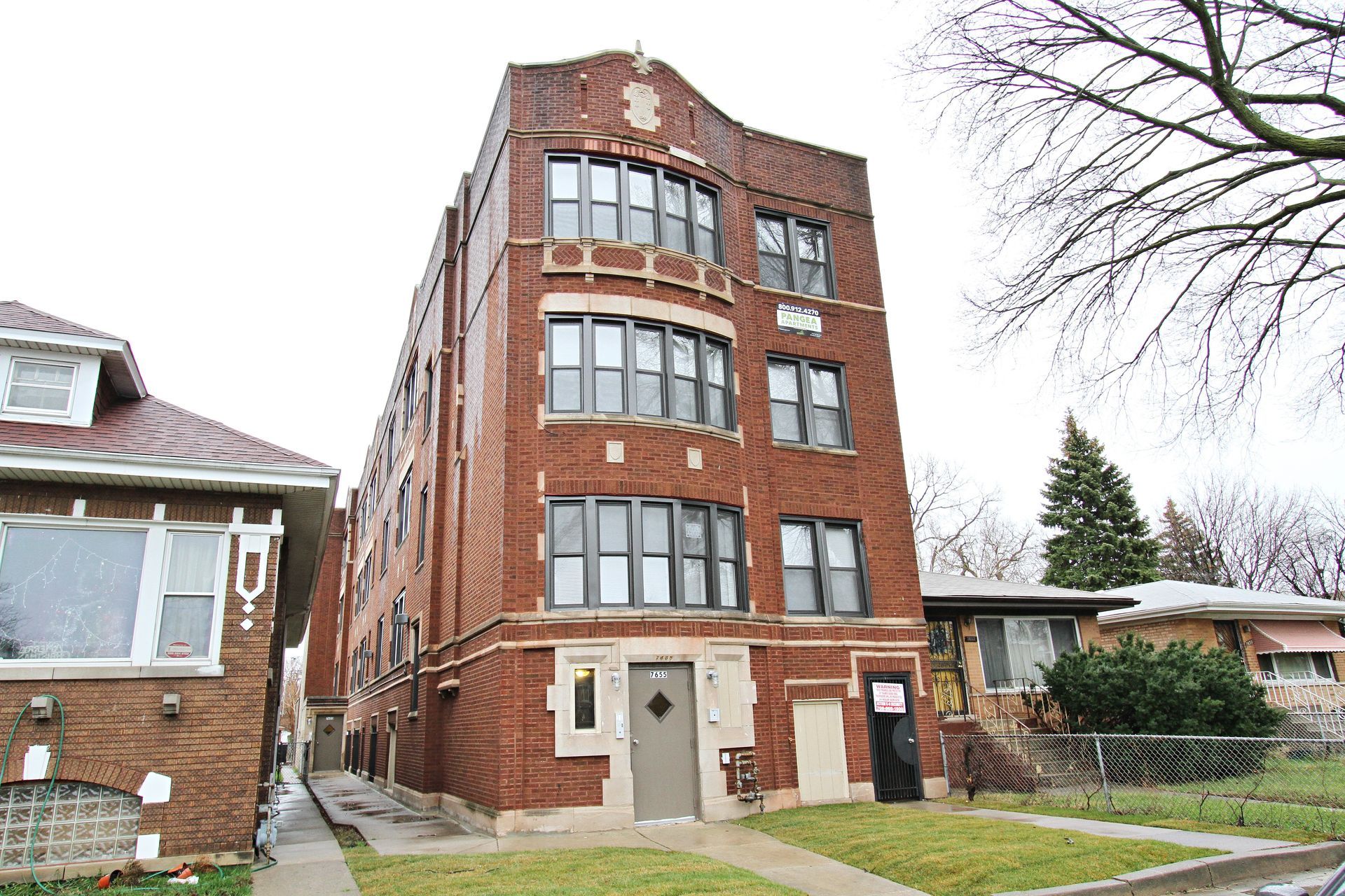 Red brick apartment building with multiple windows; overcast sky.