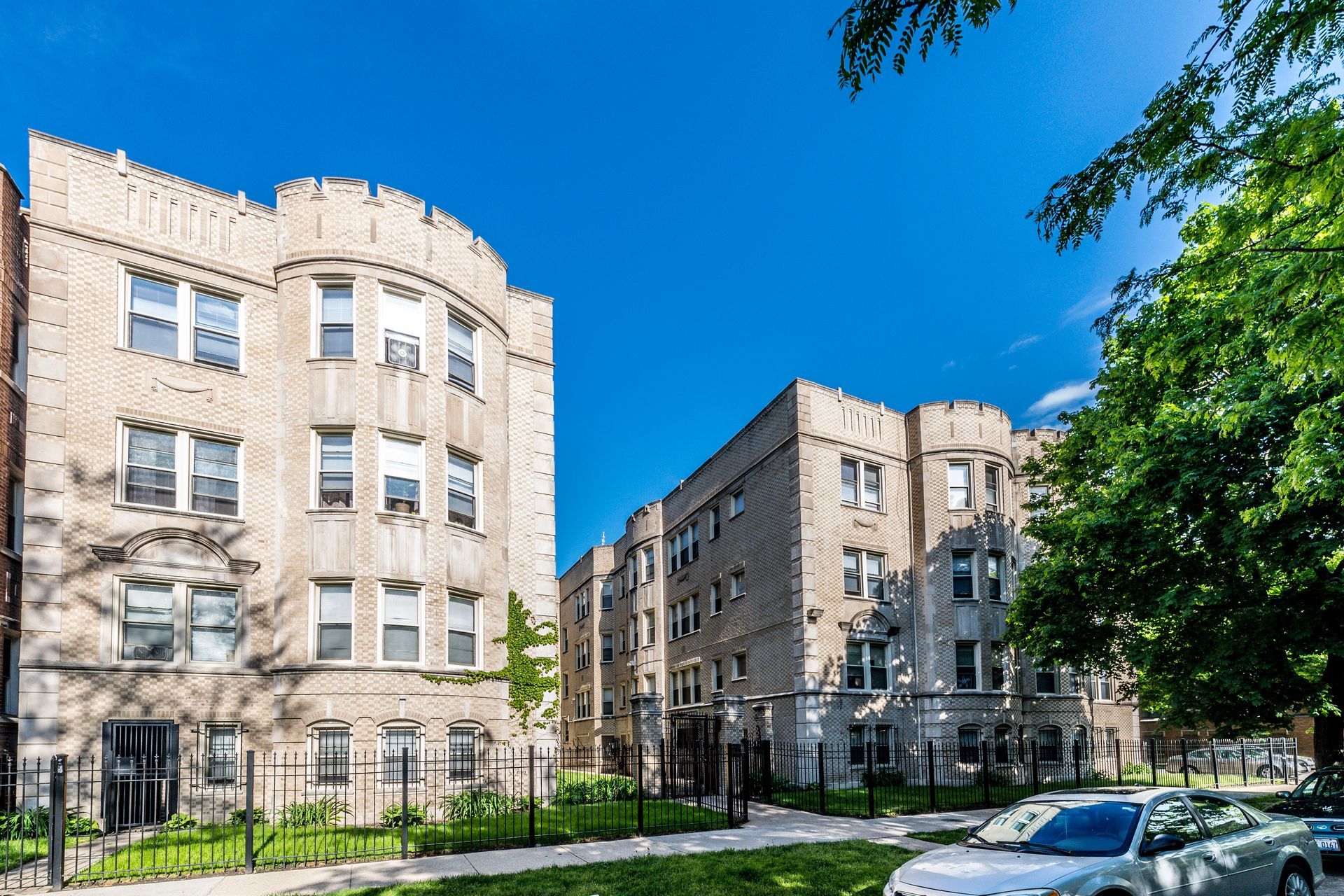 Two multi-story brick apartment buildings under a bright blue sky.